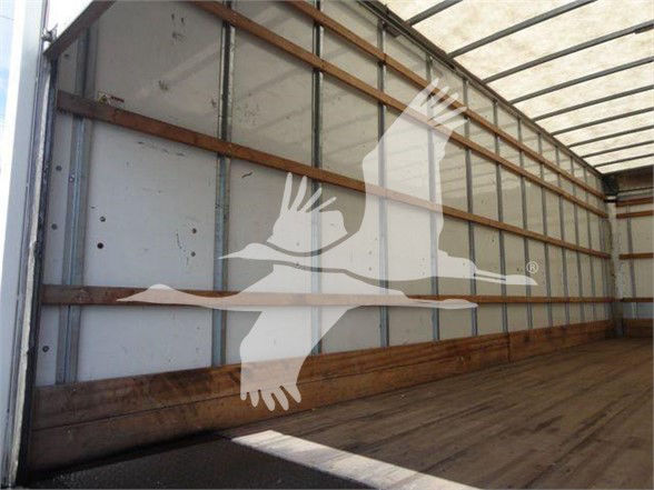 Box truck trailer interior with wooden side rails and metal walls; watermark of a bird with a long beak overlay.
