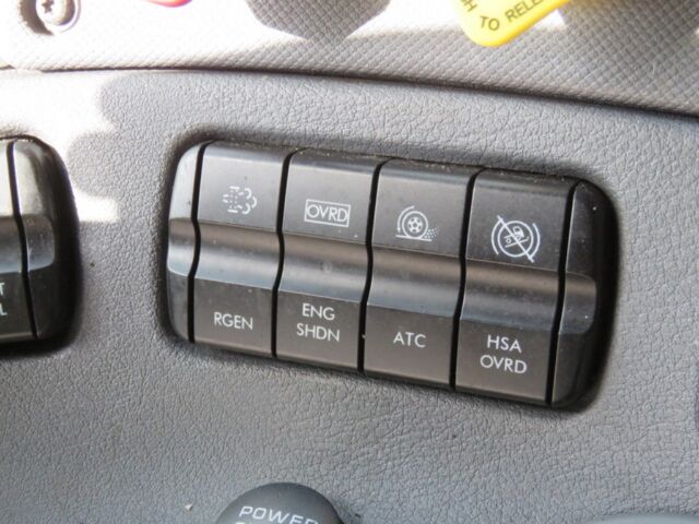 [Panel of four toggle switches in a Freightliner Cascadia Evolution interior showing RGEN, ENG SHDN, ATC, HSA OVRD with associated icons and a row of smaller buttons above.