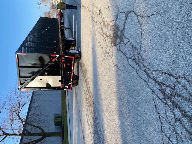 Crush car carrier trailer in a parking lot with black sides and rear doors, 48 ft length, attached to a truck.