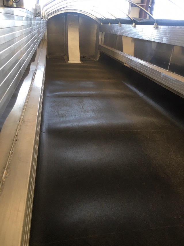 Inside the aluminum end dump trailer bed showing clean, smooth black liner with side walls and top curved roof sections.