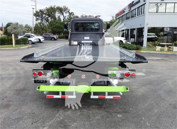 Tow truck flatbed rear view with green accents and multiple lights. Visible labels include stock number J56626; platform with safety markings.