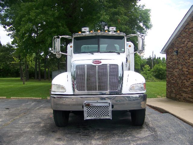 Peterbilt 335 front view showing chrome grille, bumper, and white cab with large mirrors.