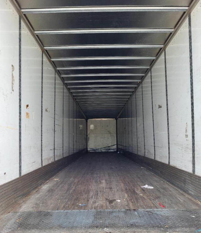 Trailer interior showing empty box trailer with metal side walls and wooden floor.