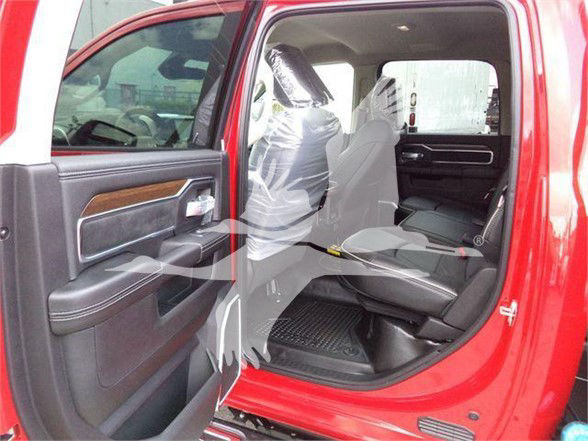 Ram 5500 Laramie interior shown with open rear door, grey leather seats, wood trim on door, and plastic seat covers.