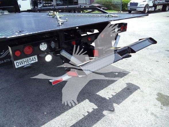 Truck bed with tow equipment and rear lights visible; license plate DW H6545; hydraulic ramps extended.