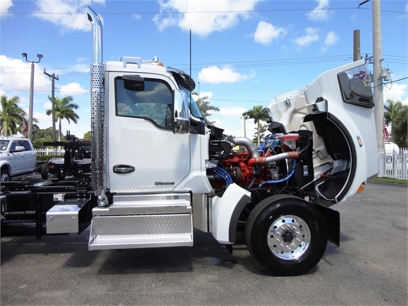 Kenworth W900 truck cab open showing engine and front wheel, with chrome steps and exposed diesel engine components.