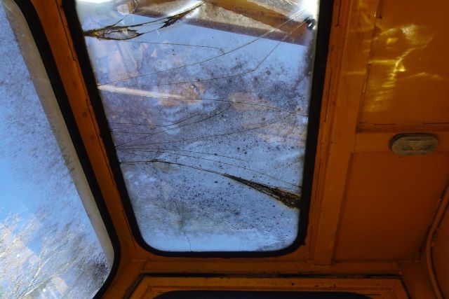 Cab interior windshield with visible scratches and reflection, orange exterior frame visible around window.