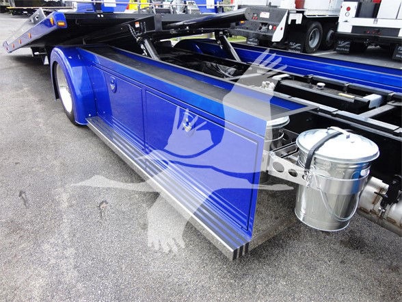 Blue Peterbilt 337 utility truck side view showing polished fuel tanks and underbody steps with a reflective surface.