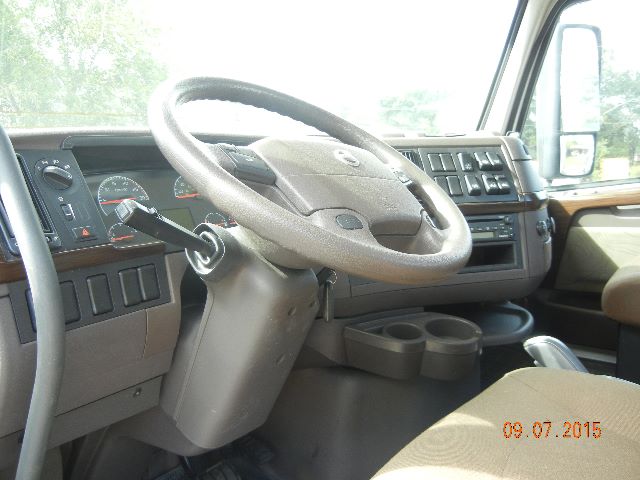 Volvo truck cab interior showing steering wheel and dashboard with cup holders.