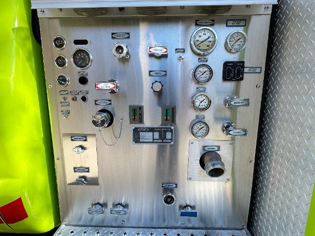 Control panel of a 2001 Ford F550 fire truck showing gauges, valves, and switches on a metallic panel.