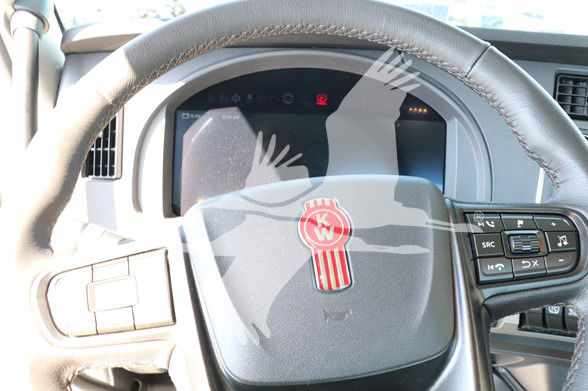 Kenworth T880 steering wheel and instrument cluster visible through steering wheel with Kenworth emblem.