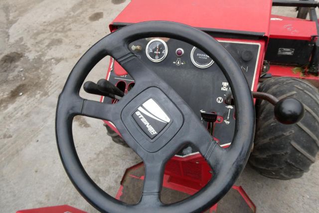 Steering wheel and dash of a red Steiner 415 agricultural truck equipment showing gauges and controls.