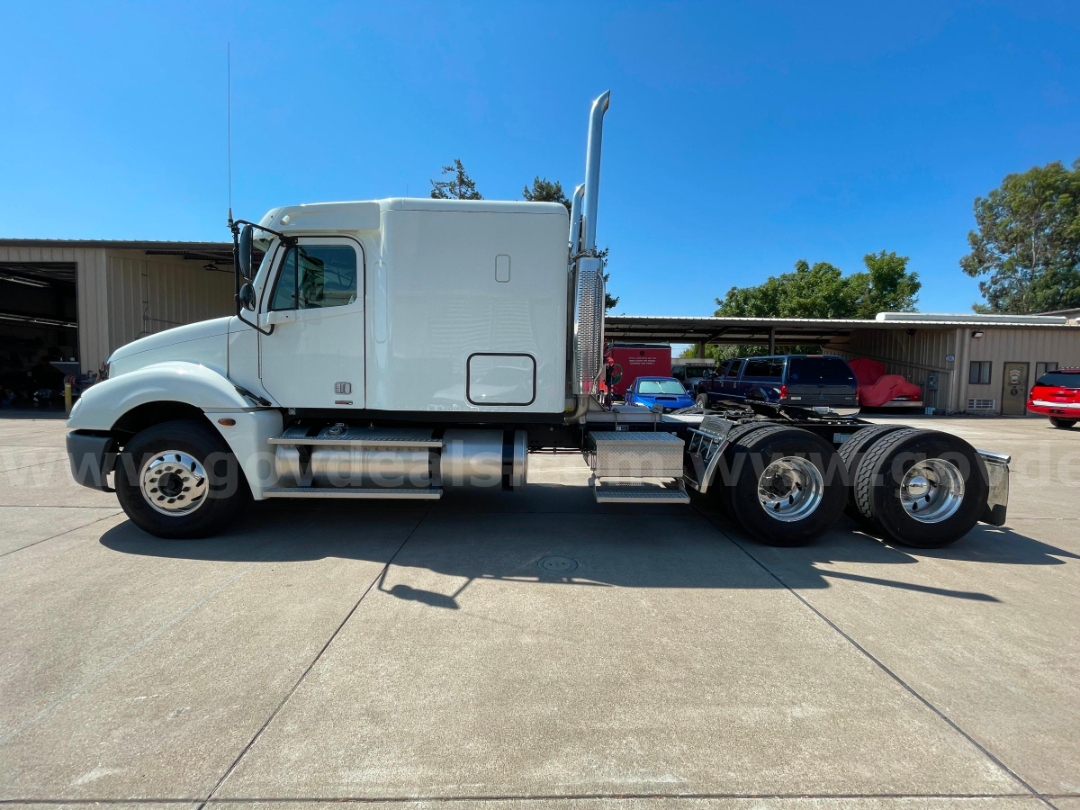 Truck side profile of a white 2004 Freightliner Columbia 120 cab and chassis showing solo cab, dual rear axles, exhaust stack, and fuel tanks.