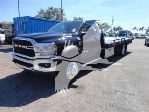 2024 Ram 5500 SLT blue and white tow truck front-left view with long flatbed. Visible text on grille reads RAM; RAM badge on hood; no other legible text visible.