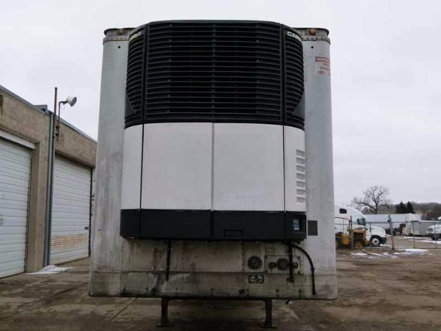Trailer refrigeration unit mounted to the front of a 48-foot trailer with Grains? brand label on the top right; concrete landing legs and hitch visible at base.