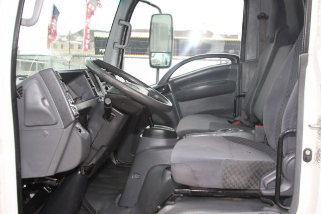 Isuzu NPR-HD cab interior showing steering wheel, dashboard, and front seats.