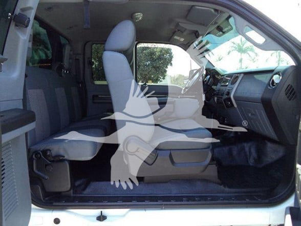 Ford F650 cab interior showing front seats, dashboard, and open doorway. Light-colored upholstery, steps on door threshold, steering wheel visible.