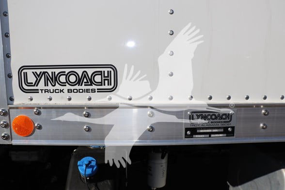 Isuzu truck box side showing Lyncoack Truck Bodies logo and a metal plate with Troy Alabama text.