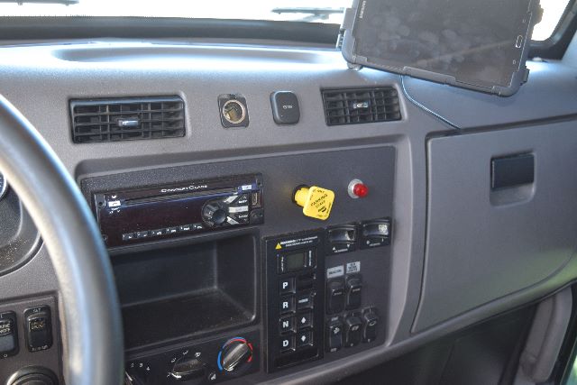 Peterbilt truck dashboard showing stereo head unit, ignition switch, yellow kill switch, gauge cluster area, and control panel with gear selector and switches.