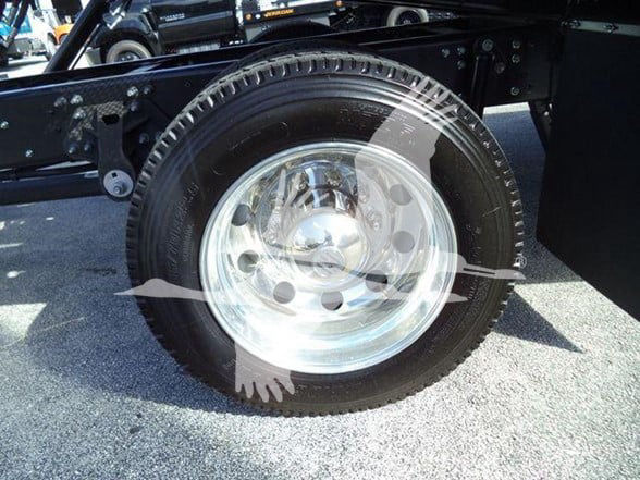 Front wheel and suspension area of a 2025 Hino 268A truck showing a polished steel wheel and tire.