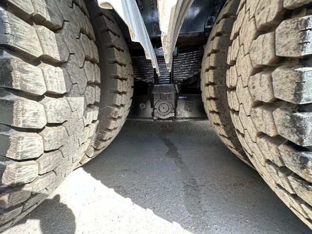Underbody view between dual rear axles of a 2013 International 7500 vacuum truck showing drivetrain differential and leaf springs.