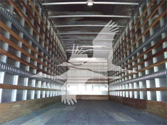 Interior of a box truck cargo area with metal sidewalls and wooden floor. Overlay silhouette of a bird logo.