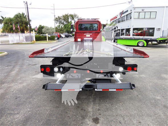 Tow truck chassis rear view with flatbed and rear lights; Peterbilt badge visible on cab in background.