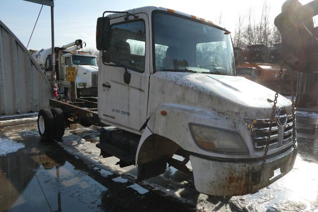 Front-left view of a white 2007 Hino 145 cab and chassis truck with dirt and mechanical components visible.