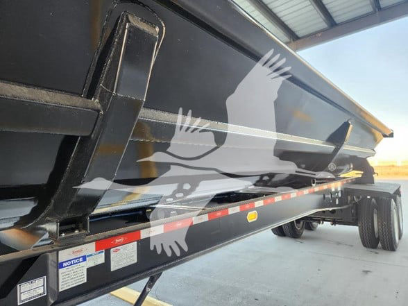Dump trailer side with SmithCo logo and reflective safety stripes, showing undercarriage and wheels.