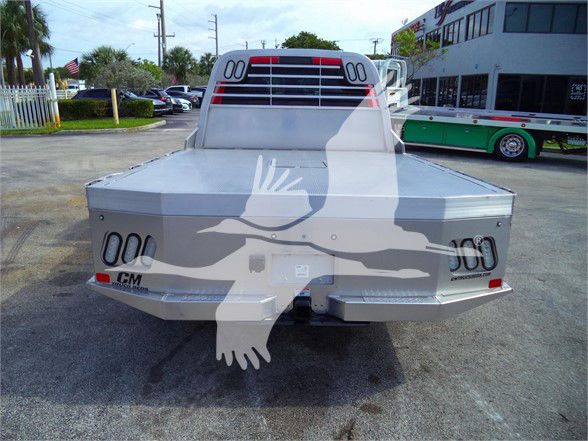 Ram 5500 flatbed truck rear view with metal flatbed, tail lights, and CM branding.