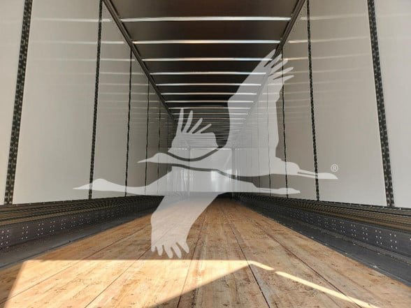 Interior of a newly built Wabash trailer with wooden floor and side rails, showing empty cargo area. No visible text beyond watermark-like logo.