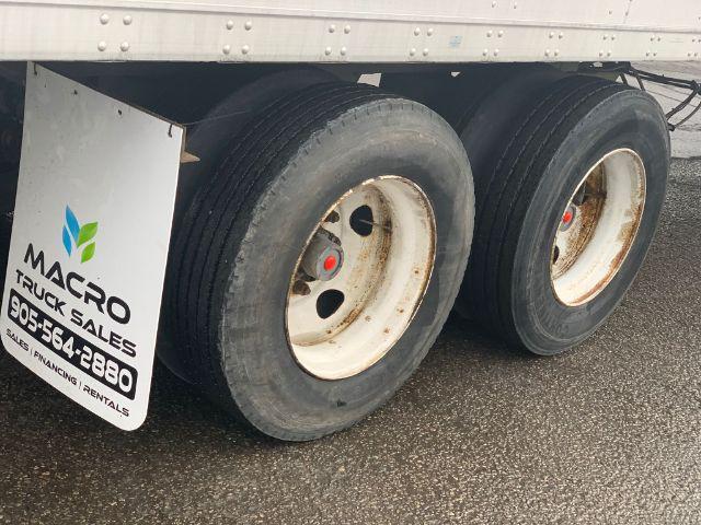 Dual rear wheels of a 2013 Stoughton dry van trailer with white rims and mudflap showing Macro Truck Sales sign.
