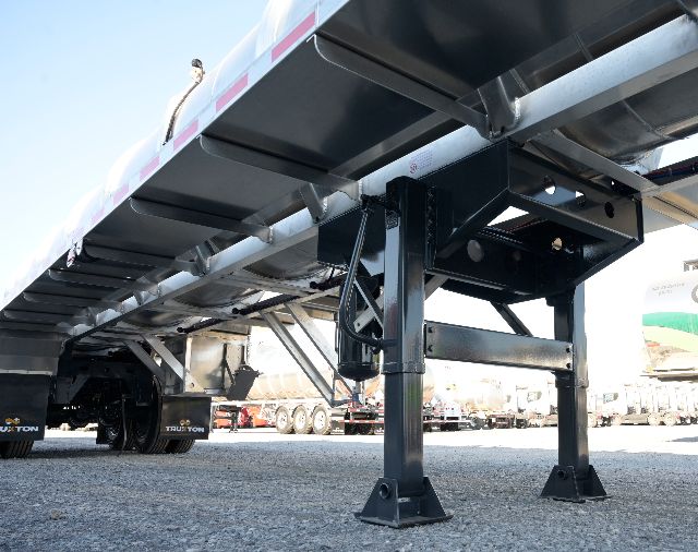 Aluminum vacuum trailer undercarriage with black steel support members and landing gear legs visible.