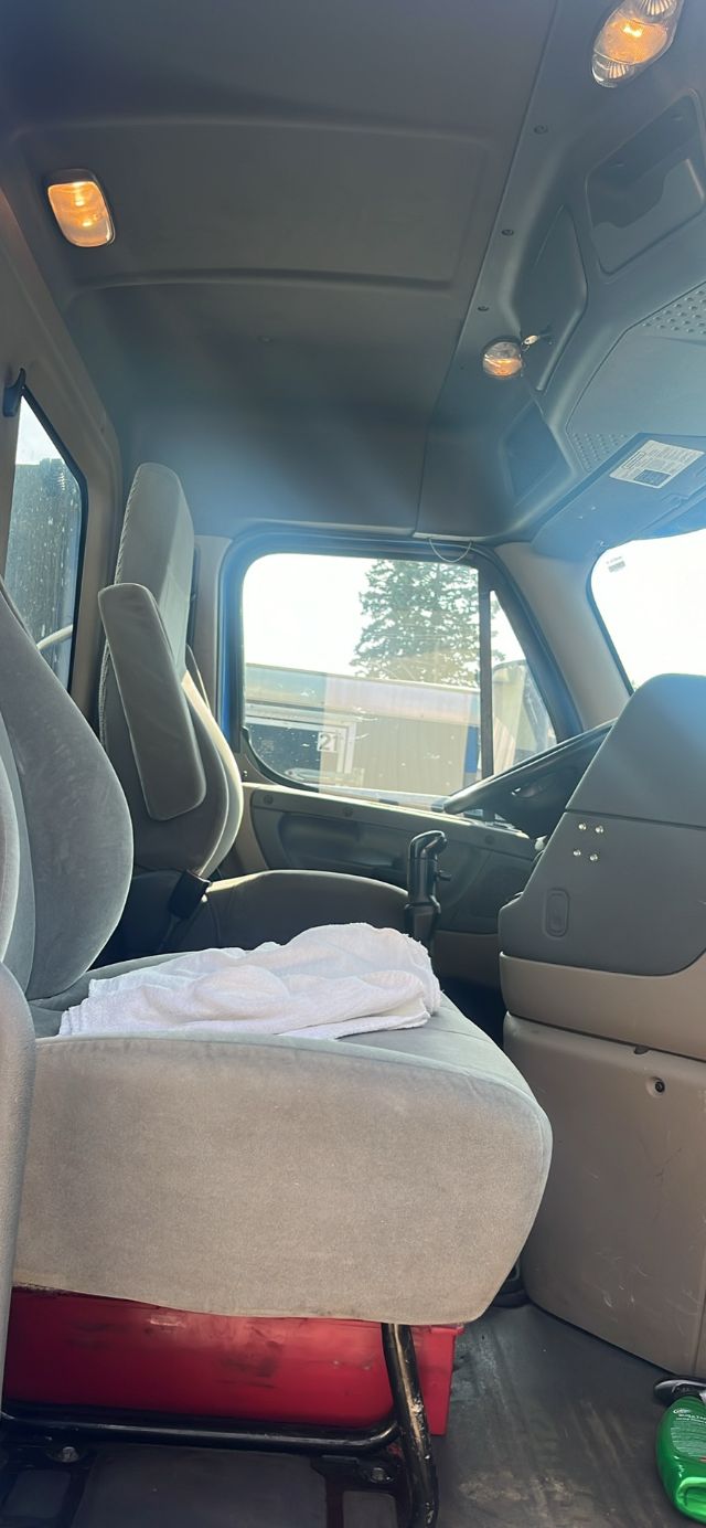Cab interior of a 2016 Freightliner Cascadia sleeper/Daycab showing front seats and overhead console with small lights.