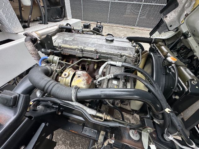 GMC W5500 engine bay showing exposed inline diesel engine with intake manifold, hoses, and turbocharger lines.