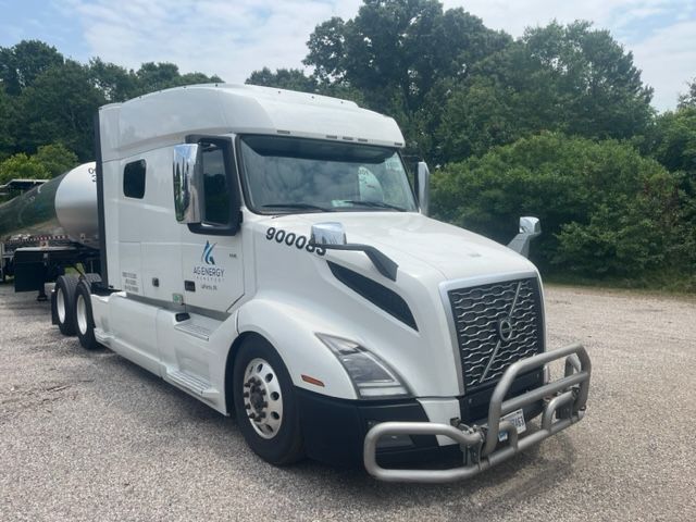 Volvo VNL64T740 tractor unit in white with front grille guard, alcohol lights, and company logo on door. Displays 900083 stock number and Volvo emblem.