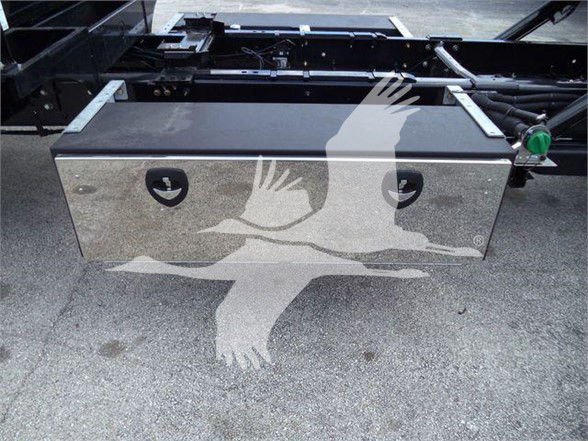 Truck chassis with a silver rectangular tool/storage box mounted, green latch on the right, metal frame undercarriage visible.