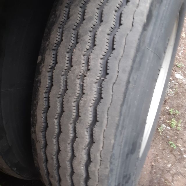Tire treads close-up on a Fontaine Revolution 52 trailer wheel shown in a flatbed trailer context.