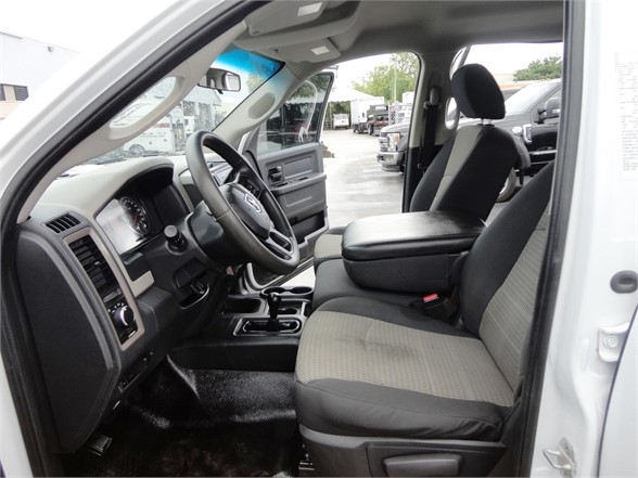 Ram 3500 interior showing front seats, dashboard, and steering wheel from driver side; black and gray cloth seats with center console.