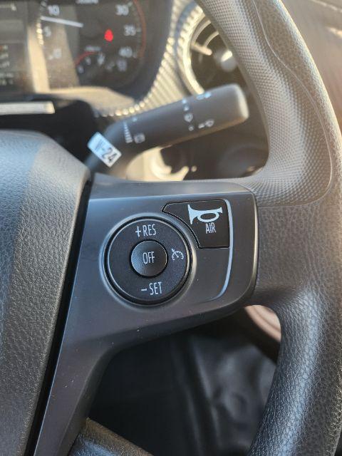 Inside view of a 2025 Hino L6 steering wheel with cruise control buttons on left, and part of instrument cluster in background.