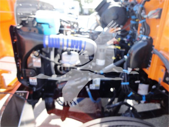 Peterbilt engine bay with blue coolant hose and various components visible; portion of radiator and hoses seen through grille. No explicit text legible.