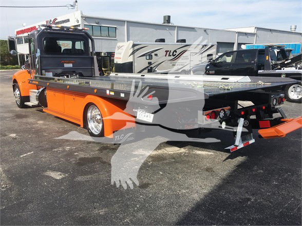 2022 Peterbilt 337 tow truck in orange with flatbed, rear view showing platform and towing equipment.