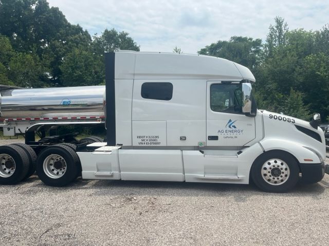 Side view of a white Volvo VNL truck with sleeper cab. Visible text includes 'US DOT # 31 125' 'MC 100120' 'VIN 4V4NC9EH0KN900083' and company logo 'AG ENERGY' with location 'Lakeland, FL'. Also number '900083' on door and fuel/tank area.