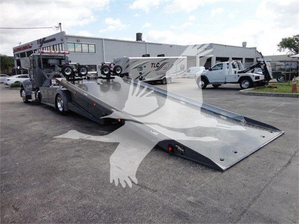 Tow truck with a wide flatbed trailer in a dealership lot, 2022 Peterbilt 337 listing, VIN visible in header area.