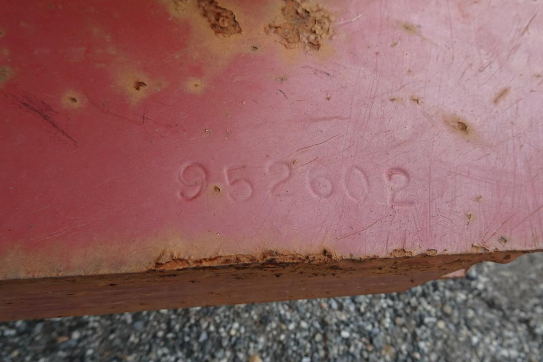 Stamp on pink metal showing number 952602 (or 9-5-7? unclear) with rust at edge.