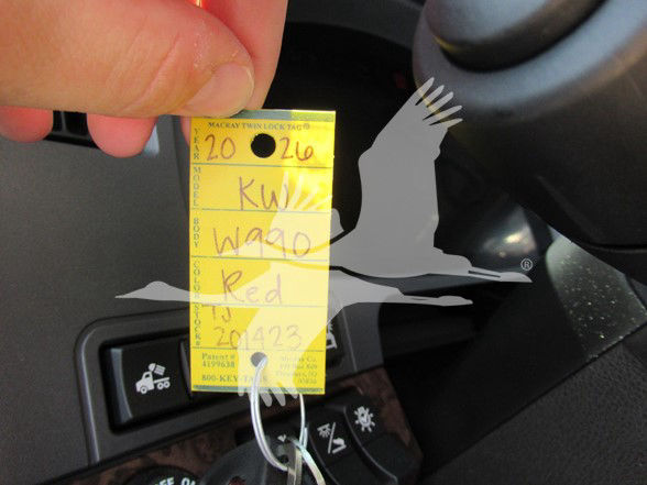 Key tag hanging from Kenworth W990 ignition area with handwritten numbers and letters on yellow tag.