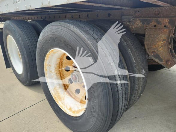 Dual rear wheels on a trailer axle with visible rusted steel rim and black tire treads.