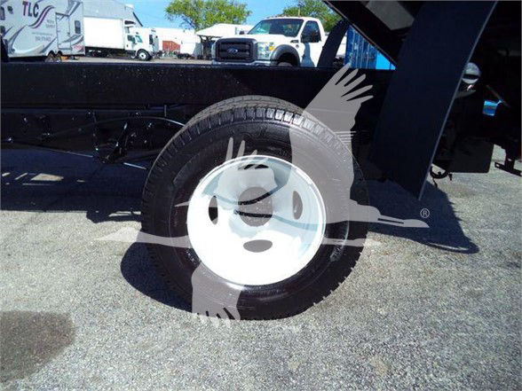 Ford E450 dump truck wheel and part of the dump bed, seen in a truck lot.