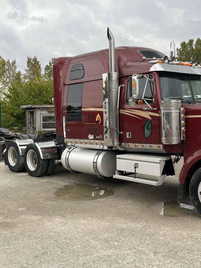 Truck side view showing maroon 2007 Western Star with Detroit 14L badge, chrome exhaust stacks, and aluminum fuel tanks.