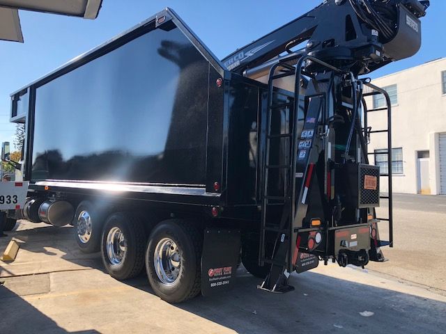 2018 Peterbilt 567 grapple truck with black dump body and crane, side view showing chrome wheels and access ladders.